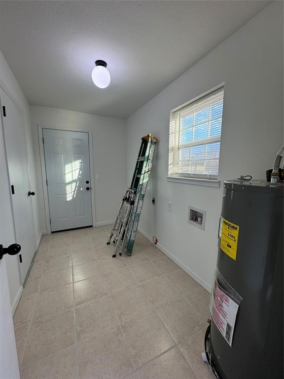 foyer entrance with water heater and a textured ceiling