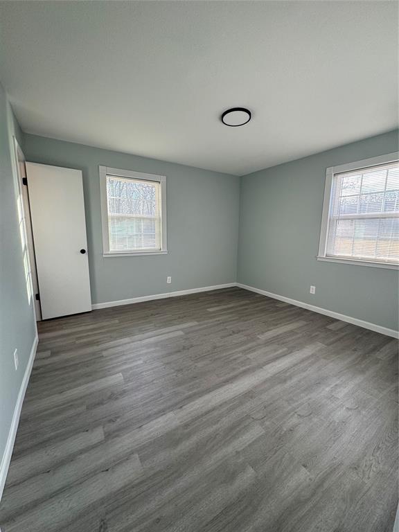 spare room with plenty of natural light and dark hardwood / wood-style floors