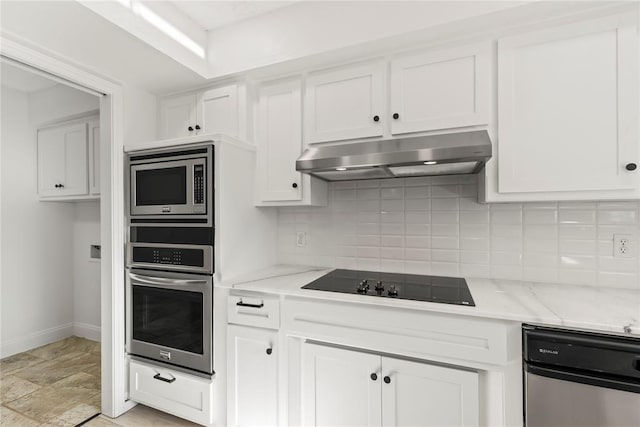 kitchen with appliances with stainless steel finishes, range hood, light stone counters, tasteful backsplash, and white cabinets