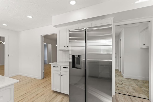 kitchen featuring white cabinetry, stainless steel fridge with ice dispenser, light hardwood / wood-style flooring, and a textured ceiling