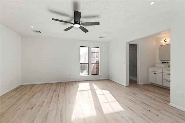 interior space with sink, light hardwood / wood-style flooring, and a textured ceiling