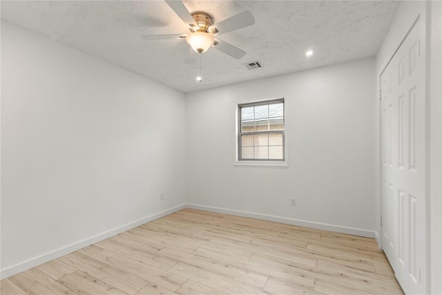 empty room with a textured ceiling, light hardwood / wood-style floors, and ceiling fan