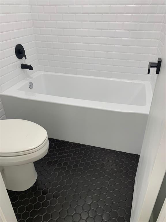 bathroom with a washtub, tile patterned flooring, and toilet