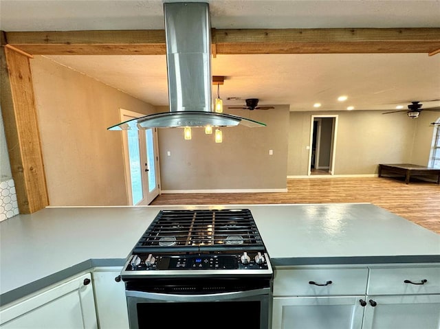 kitchen with island exhaust hood, stainless steel range with gas stovetop, ceiling fan, and light hardwood / wood-style flooring