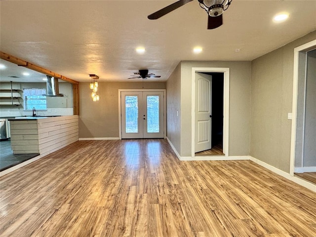 unfurnished living room featuring french doors, ceiling fan, a wealth of natural light, and light wood-type flooring