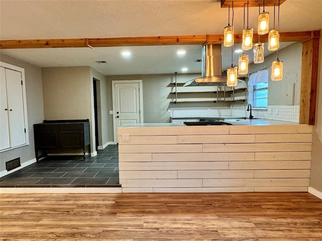 kitchen with island range hood, pendant lighting, wood-type flooring, a wood stove, and decorative backsplash