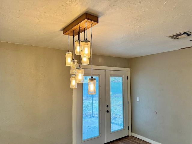 entryway with french doors, a healthy amount of sunlight, dark hardwood / wood-style floors, and a textured ceiling