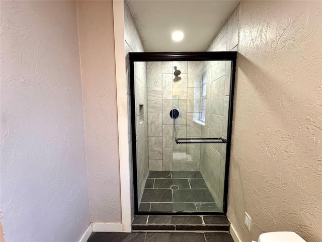 bathroom featuring toilet and a shower with door