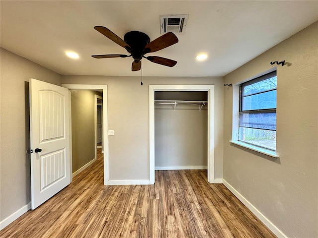 unfurnished bedroom with wood-type flooring, ceiling fan, and a closet