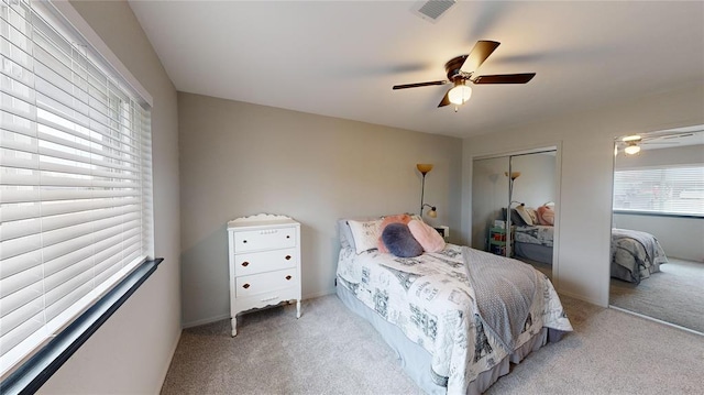 carpeted bedroom featuring ceiling fan and a closet