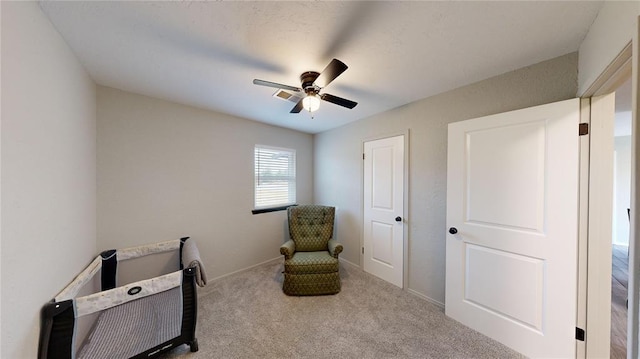 living area featuring light carpet and ceiling fan