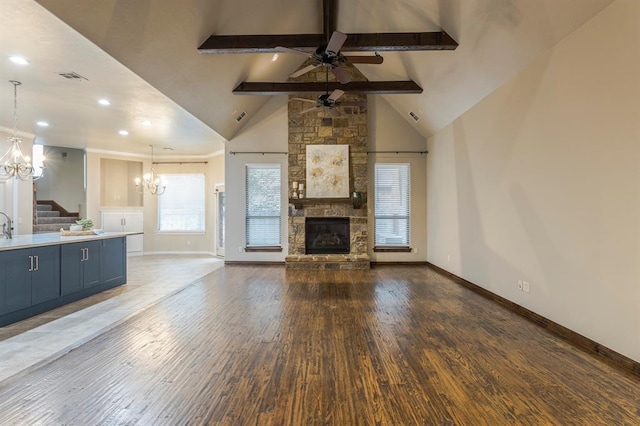 unfurnished living room featuring dark hardwood / wood-style floors, ceiling fan with notable chandelier, high vaulted ceiling, a fireplace, and beam ceiling