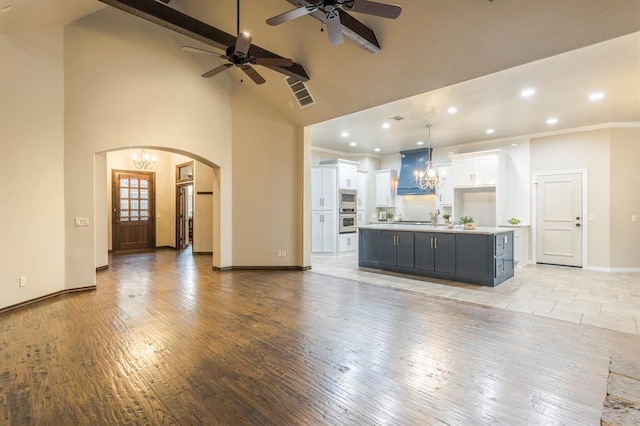 unfurnished living room featuring crown molding, high vaulted ceiling, light hardwood / wood-style floors, beamed ceiling, and ceiling fan with notable chandelier