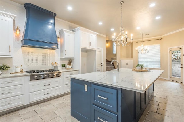 kitchen with premium range hood, stainless steel gas cooktop, an island with sink, and white cabinets