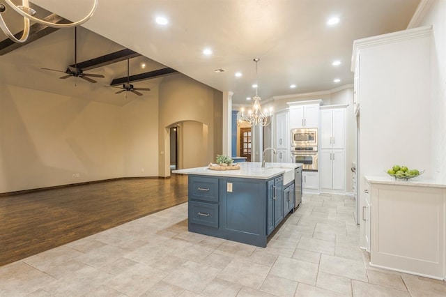 kitchen featuring blue cabinetry, a kitchen island with sink, hanging light fixtures, stainless steel appliances, and white cabinets