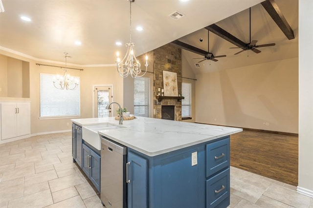 kitchen featuring blue cabinets, sink, hanging light fixtures, stainless steel dishwasher, and a center island with sink