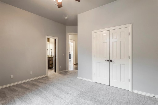 unfurnished bedroom with ensuite bathroom, light carpet, ceiling fan, and a closet