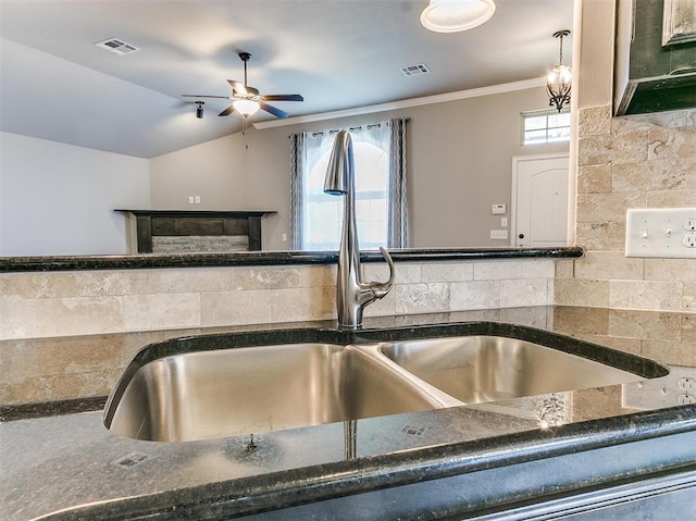 kitchen with sink, tasteful backsplash, vaulted ceiling, ornamental molding, and ceiling fan