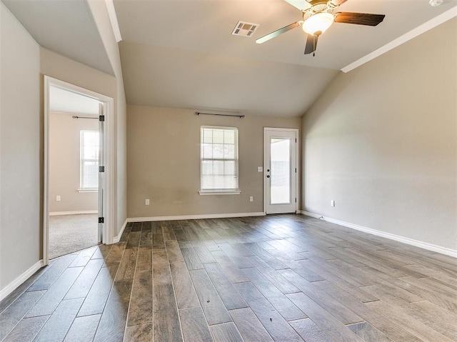 empty room featuring ceiling fan, plenty of natural light, vaulted ceiling, and wood-type flooring