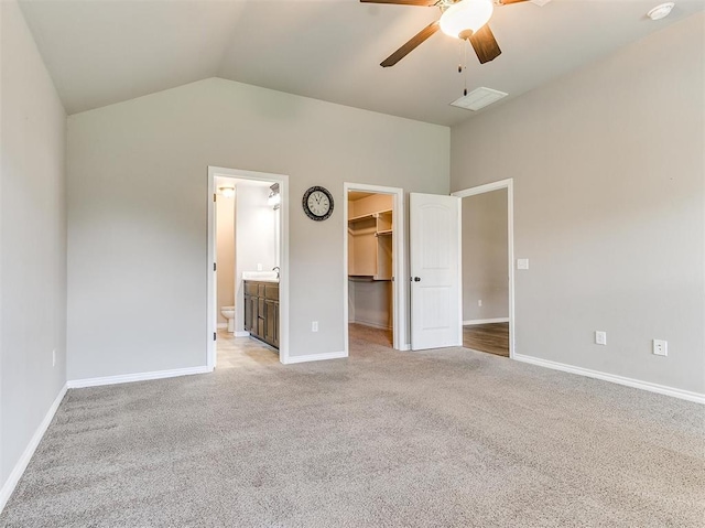 unfurnished bedroom featuring lofted ceiling, a spacious closet, light colored carpet, ceiling fan, and a closet