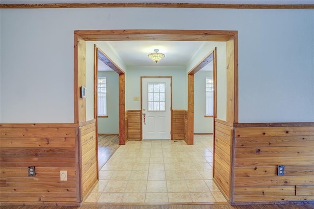 doorway with light tile patterned floors and wooden walls