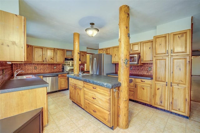 kitchen with tasteful backsplash, sink, a kitchen island, and appliances with stainless steel finishes