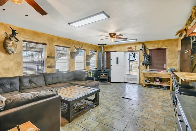 living room featuring a wood stove and ceiling fan