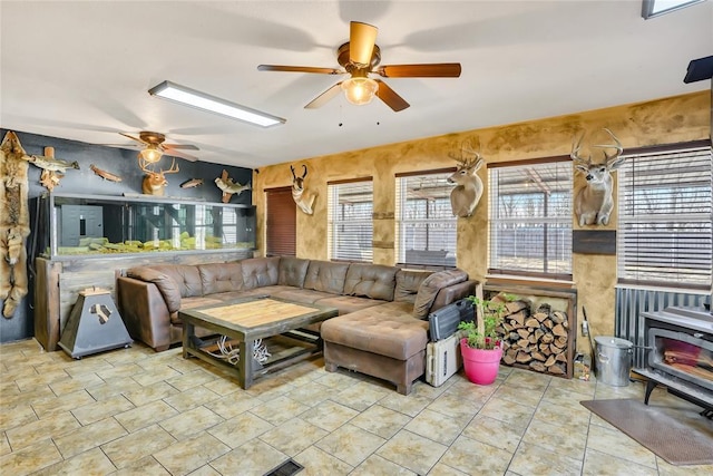 living room with light tile patterned floors, ceiling fan, and a wood stove