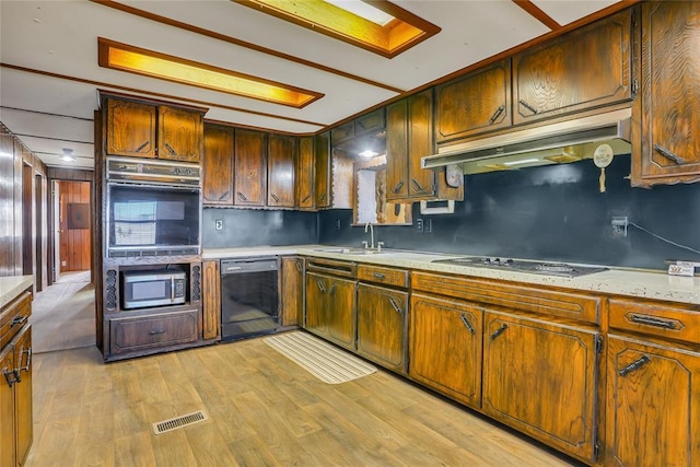 kitchen featuring tasteful backsplash, sink, black appliances, and light wood-type flooring