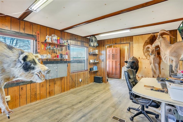 home office featuring beam ceiling, light wood-type flooring, and wood walls