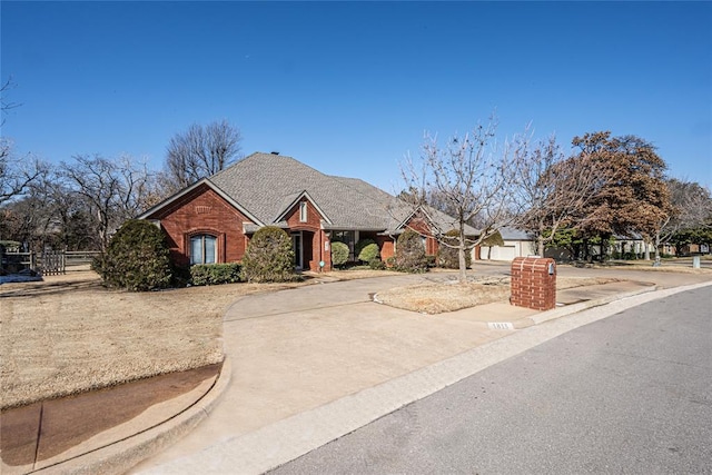 view of front of property featuring concrete driveway, brick siding, and roof with shingles