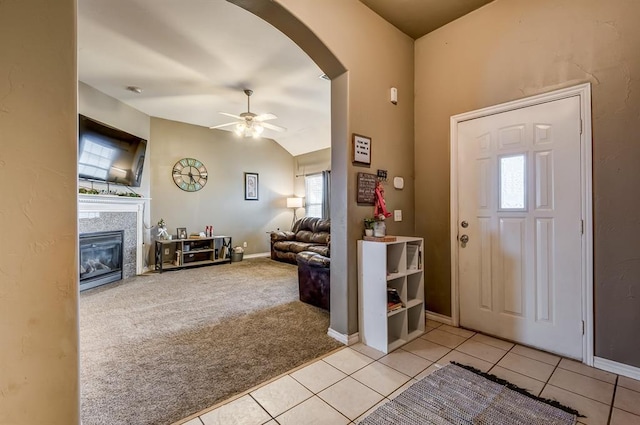 carpeted foyer entrance with a fireplace, ceiling fan, and vaulted ceiling