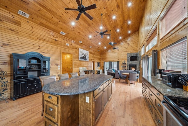 kitchen featuring light hardwood / wood-style floors, a center island, high vaulted ceiling, and wood walls