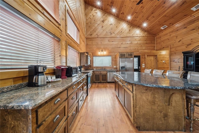 kitchen with a breakfast bar, wood ceiling, high vaulted ceiling, stainless steel appliances, and a large island