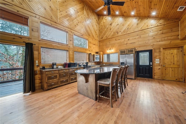 kitchen with wood ceiling, stainless steel fridge with ice dispenser, light wood-type flooring, wooden walls, and a kitchen island