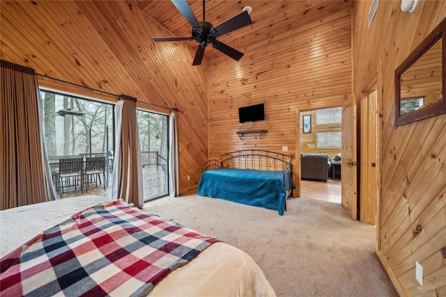 bedroom with access to exterior, a high ceiling, light carpet, and wood walls