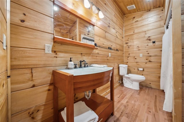 bathroom with hardwood / wood-style flooring, wood walls, wood ceiling, and toilet