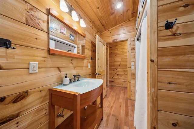 bathroom featuring lofted ceiling, wood ceiling, wood-type flooring, vanity, and wooden walls