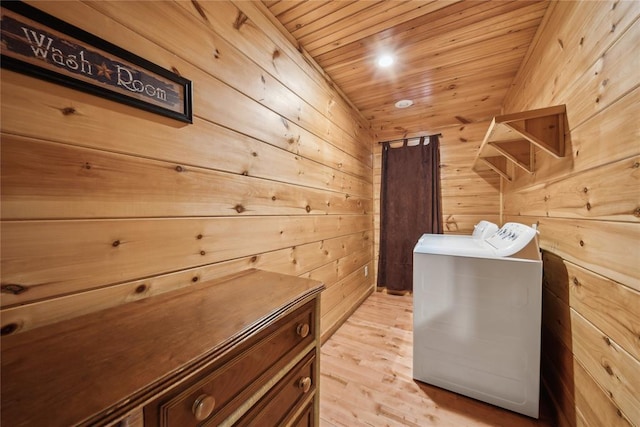 clothes washing area featuring light hardwood / wood-style flooring, wood ceiling, washer and clothes dryer, and wood walls