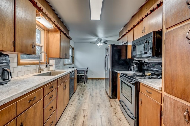 kitchen featuring sink, decorative backsplash, ceiling fan, black appliances, and light hardwood / wood-style flooring