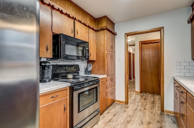 kitchen featuring appliances with stainless steel finishes, backsplash, and light wood-type flooring