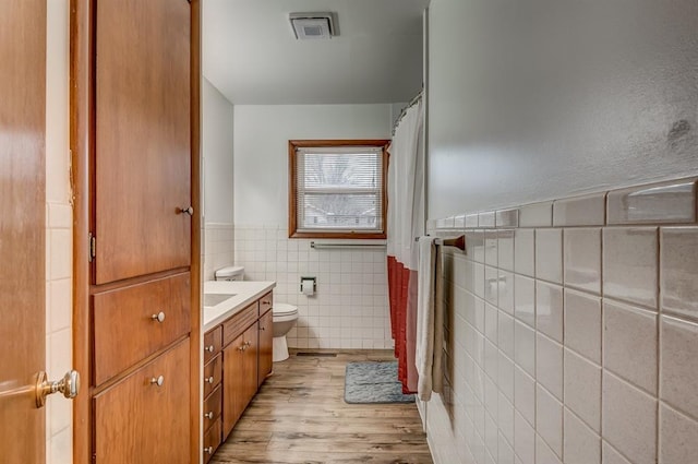 bathroom with hardwood / wood-style floors, vanity, tile walls, and toilet