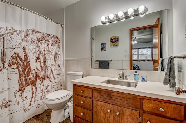 bathroom featuring vanity, toilet, and tile walls