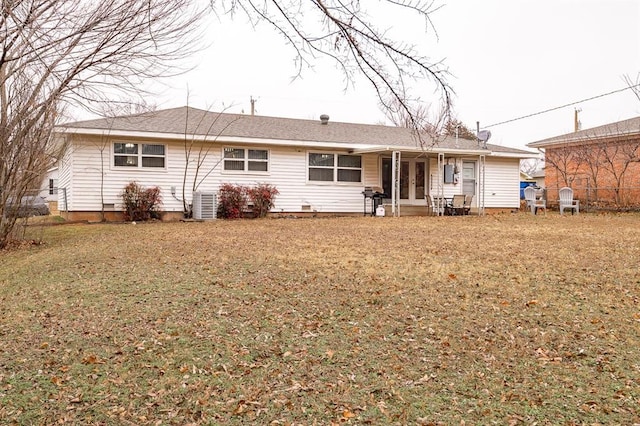 back of property with a yard and central AC