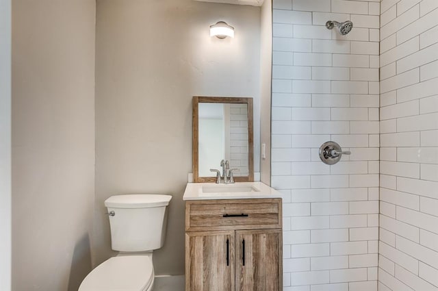 bathroom with vanity, toilet, and a tile shower