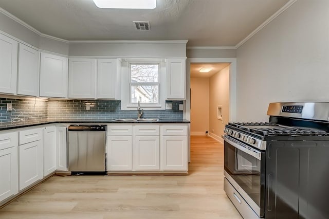 kitchen with sink, appliances with stainless steel finishes, white cabinetry, ornamental molding, and light hardwood / wood-style floors