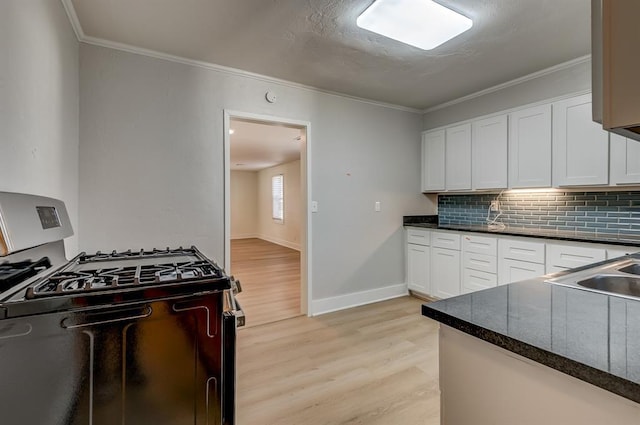 kitchen featuring white cabinetry, backsplash, ornamental molding, light hardwood / wood-style floors, and gas range