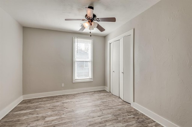 unfurnished bedroom featuring ceiling fan, light hardwood / wood-style floors, and a closet