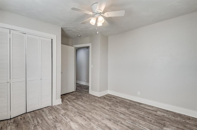 unfurnished bedroom featuring ceiling fan, light hardwood / wood-style floors, and a closet