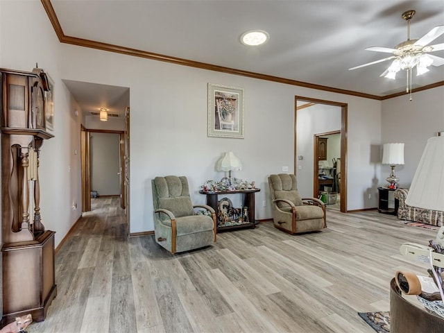 sitting room featuring ornamental molding, a ceiling fan, light wood-style flooring, and baseboards